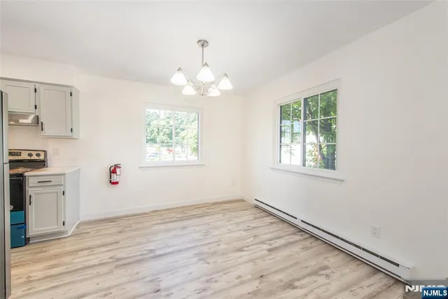 an empty room with wooden floor cabinet and windows