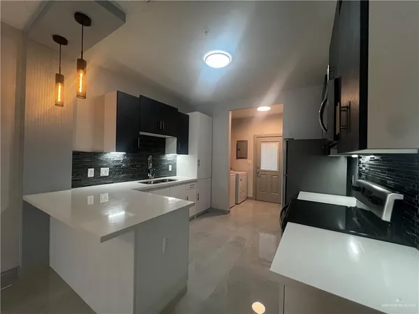 a large kitchen with stainless steel appliances a large counter top a stove and a sink