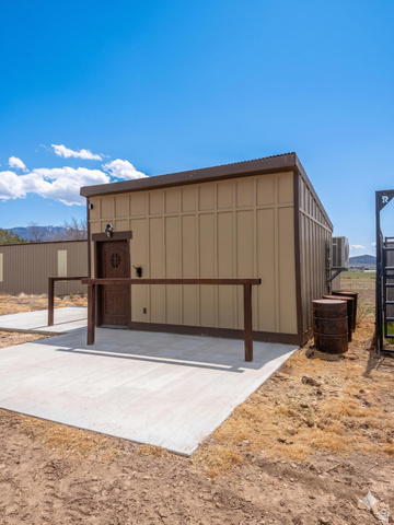 115 East 1600th Street North Santaquin, UT 84655 - Photo 34 of 52 Exterior building featuring vertical siding, a corrugated metal roof, an ornate wooden door, and a concrete patio
