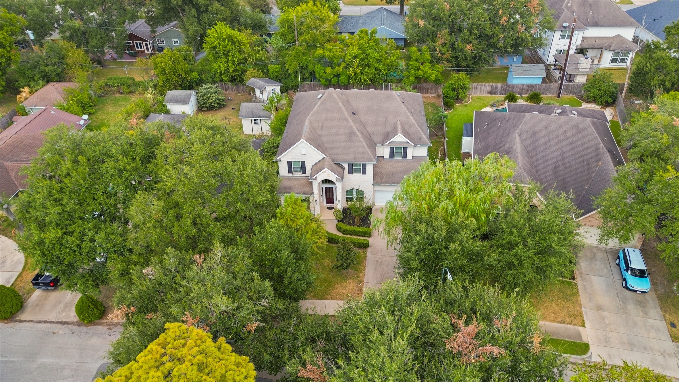 3302 Rochdale Street Houston, TX 77025 - Photo 10 of 50 Another view of your home from above, showcasing the mature tree canopy that surrounds the property and offers plenty of natural shade and privacy. The two story brick and stone exterior peeks through the greenery, with a well kept front walkway and driveway leading up to the entry. It's a picturesque setting that highlights just how established and green this neighborhood really is.