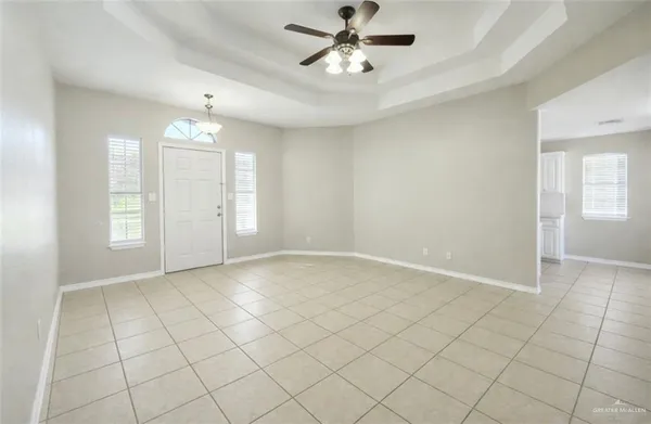 an empty room with chandelier fan and windows