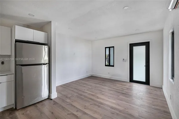 an empty room with wooden floor and a hallway