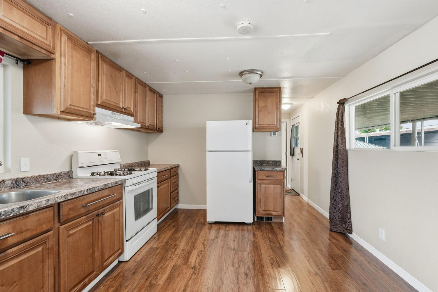 15820 Harlan Road, Unit 85 Lathrop, CA 95330 - Photo 12 of 27 a kitchen with granite countertop wooden floors and white stainless steel appliances