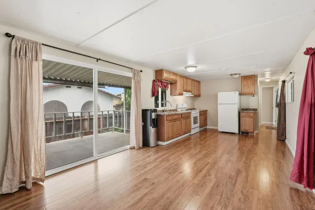 a view of a kitchen with fridge and wooden floor