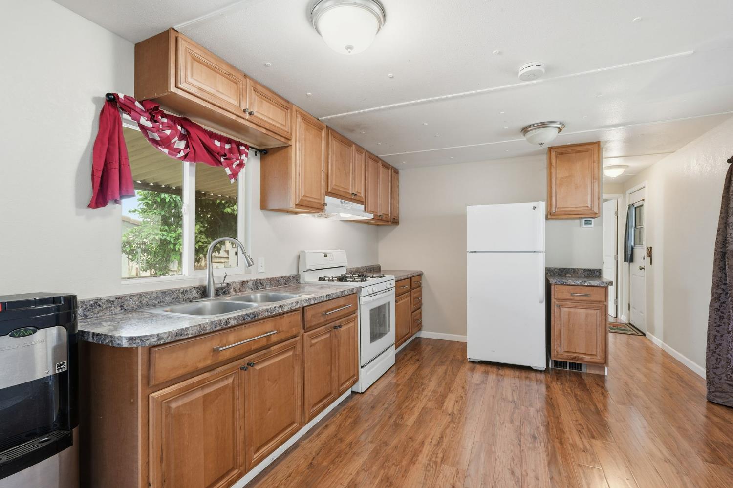 15820 Harlan Road, Unit 85 Lathrop, CA 95330 - Photo 9 of 27 a kitchen with a refrigerator a stove a sink dishwasher and wooden floor