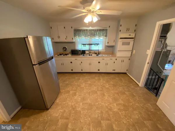 a kitchen with stainless steel appliances a refrigerator a stove a sink a refrigerator a washer dryer and white cabinets