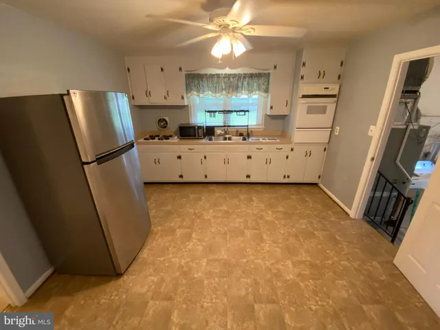 a kitchen with stainless steel appliances a refrigerator a stove a sink a refrigerator a washer dryer and white cabinets