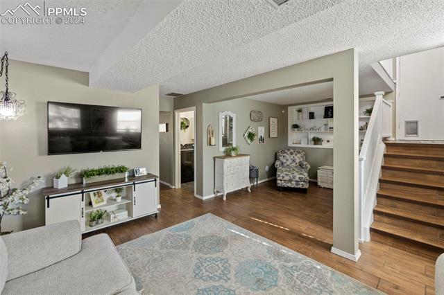 1830 Doherty Road Colorado Springs, CO 80916 - Photo 21 of 34 Living room with built in shelves, a textured ceiling, hardwood / wood-style flooring, and a chandelier