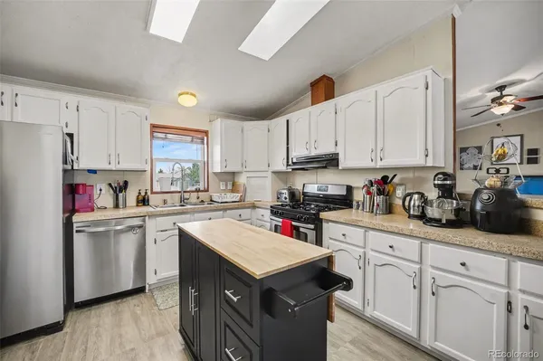 a kitchen with kitchen island a sink dishwasher stove and white cabinets with wooden floor