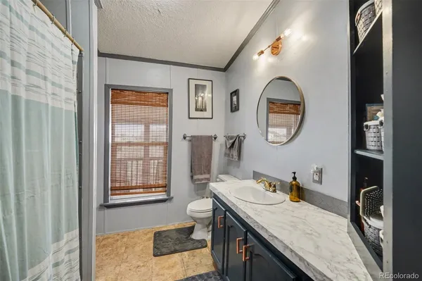 a bathroom with a granite countertop sink mirror vanity and a toilet