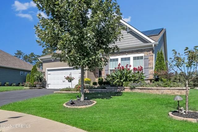 a front view of a house with a yard and tree