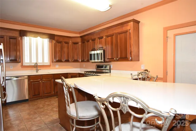 a dining room with stainless steel appliances kitchen island granite countertop a refrigerator a stove and a sink with granite countertops