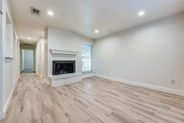 an empty room with wooden floor and fireplace