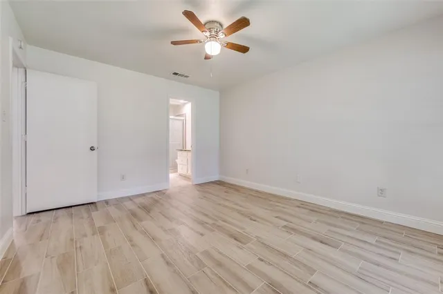 an empty room with wooden floor and a ceiling fan