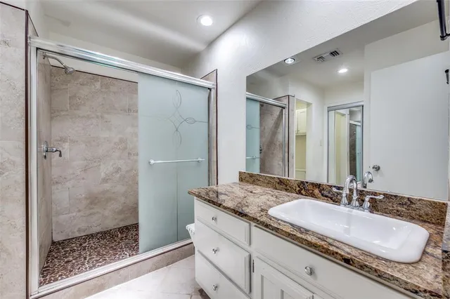 a bathroom with a granite countertop sink a mirror and shower