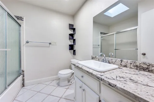 a bathroom with a granite countertop sink a toilet and a mirror