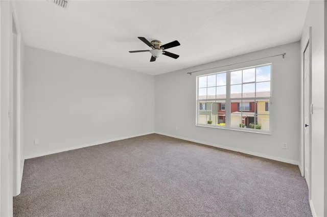 an empty room with windows and ceiling fan view