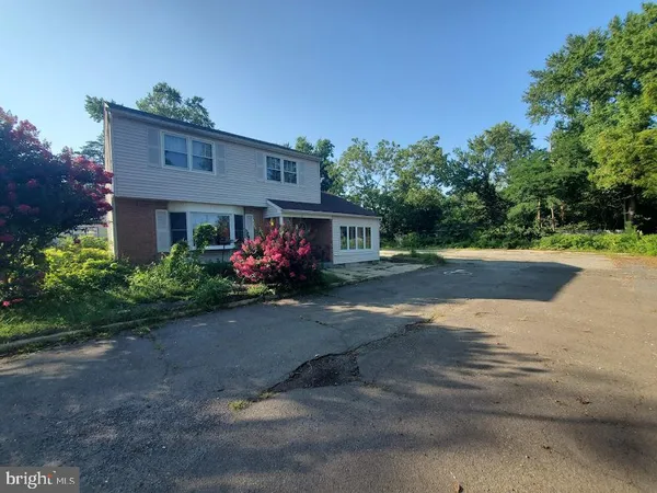 a front view of house with deck and trees in the background
