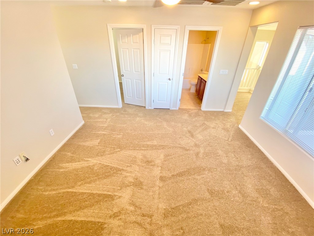 8569 Rhamus Court Las Vegas, NV 89149 - Photo 10 of 35 An inviting room boasts soft carpeting and dual entryways, leading to a private bath and additional spaces.