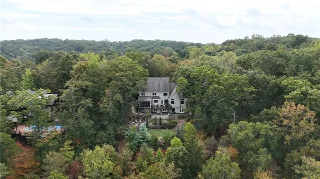 an aerial view of residential house with outdoor space and trees all around