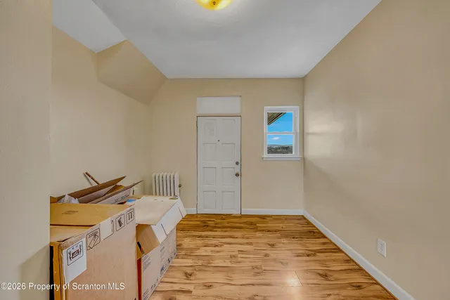 a view of a bedroom with a bed and wooden floor