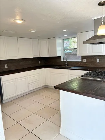 a kitchen with granite countertop a sink a stove and cabinets