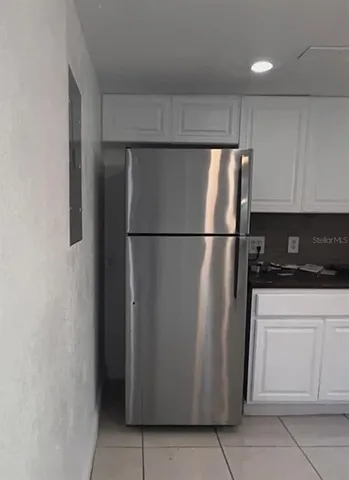 a view of a refrigerator in kitchen and white cabinets