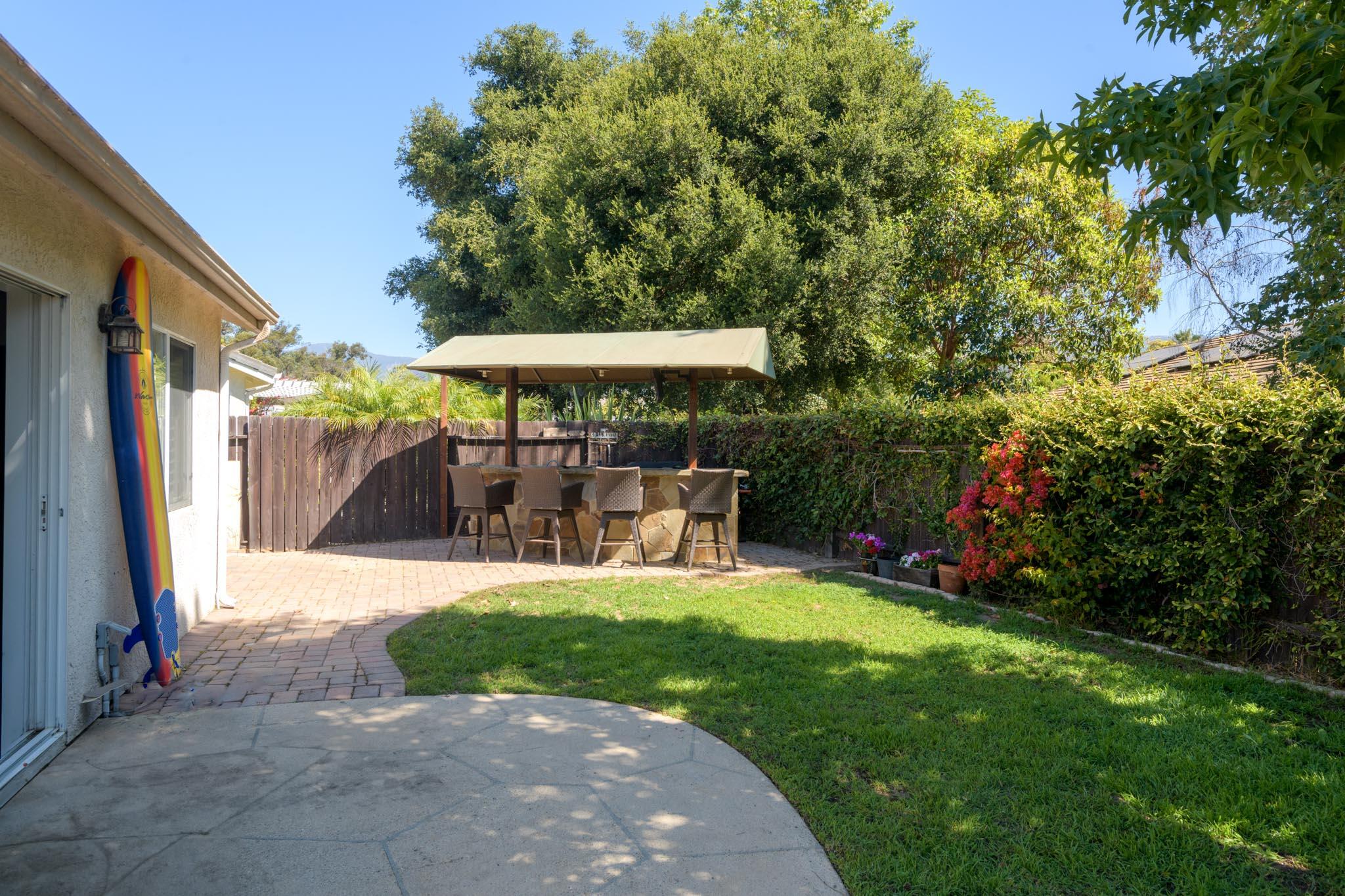 128 Gerard Drive Goleta, CA 93117 - Photo 14 of 20 a view of a patio with table and chairs under an umbrella with large trees