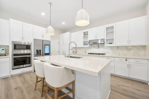 a kitchen with stainless steel appliances granite countertop a sink a stove a refrigerator and island with wooden floor