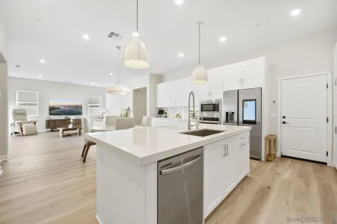 a large white kitchen with a refrigerator a stove a sink a dining table and chairs