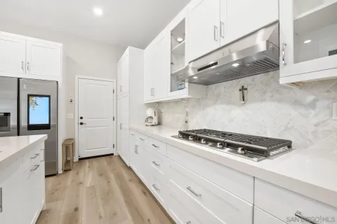 a kitchen with stainless steel appliances a stove a sink and white cabinets