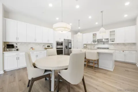 a kitchen with kitchen island a dining table chairs sink and cabinets