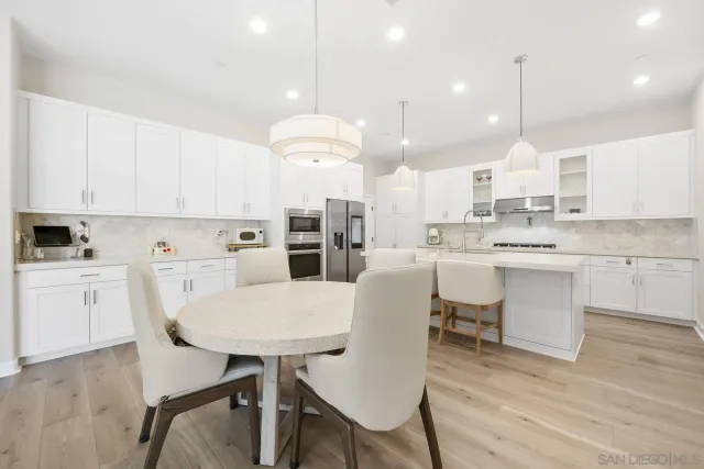 a kitchen with kitchen island a dining table chairs sink and cabinets