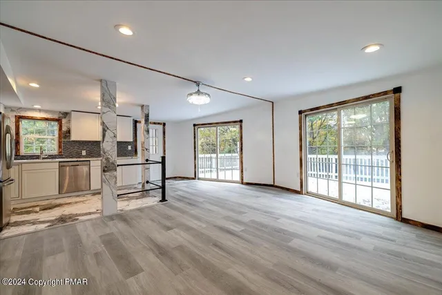 an empty room with wooden floor chandelier fan and windows