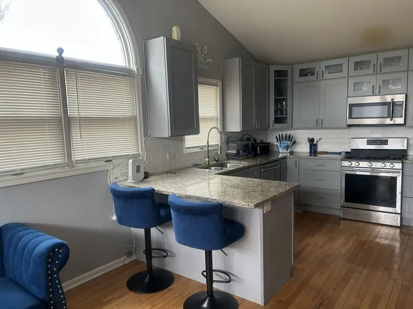 a kitchen with granite countertop a stove a sink and a refrigerator