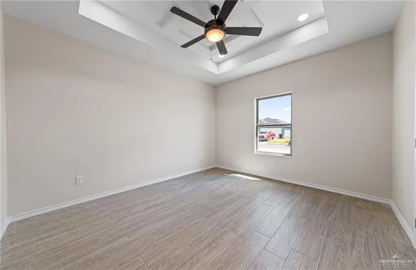 an empty room with wooden floor and ceiling fan
