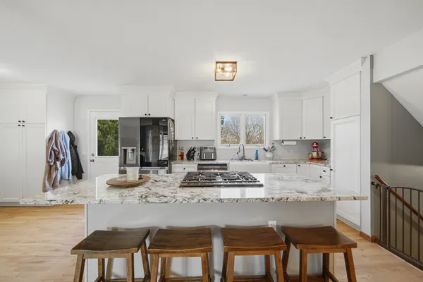 a kitchen with kitchen island granite countertop a dining table chairs and white cabinets