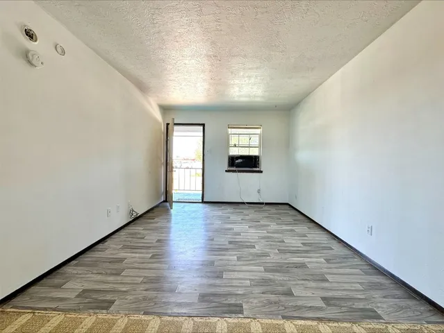 an empty room with wooden floor cabinet and windows