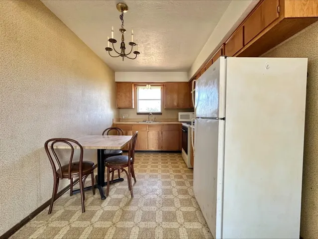 a kitchen with refrigerator and chairs
