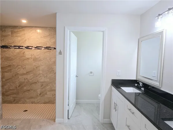 a bathroom with a granite countertop sink a toilet and shower