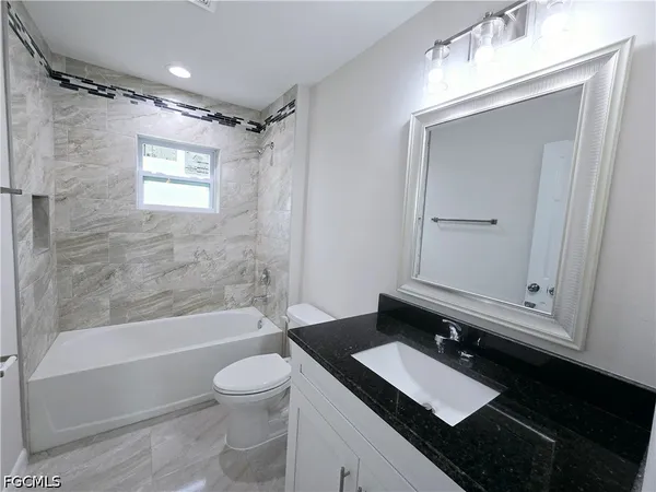 a bathroom with a granite countertop sink toilet a mirror and shower
