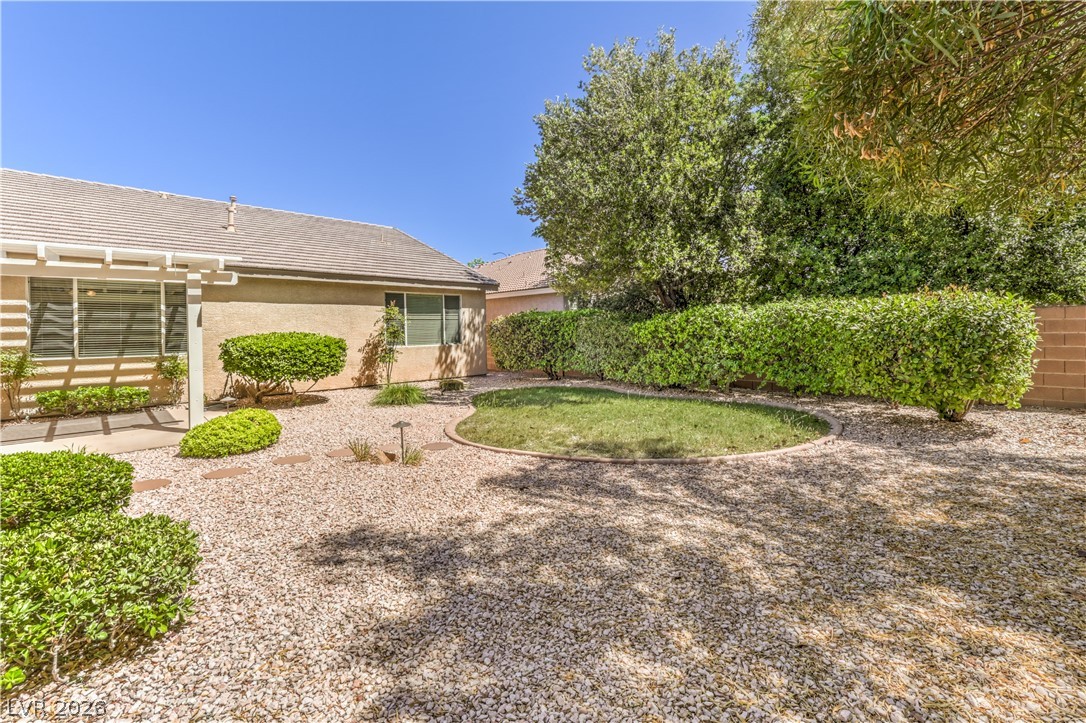 3713 Spring Shadow Road Las Vegas, NV 89129 - Photo 35 of 37 Relax in this tranquil backyard featuring a blend of natural stone, manicured shrubs, and a small grassy area.