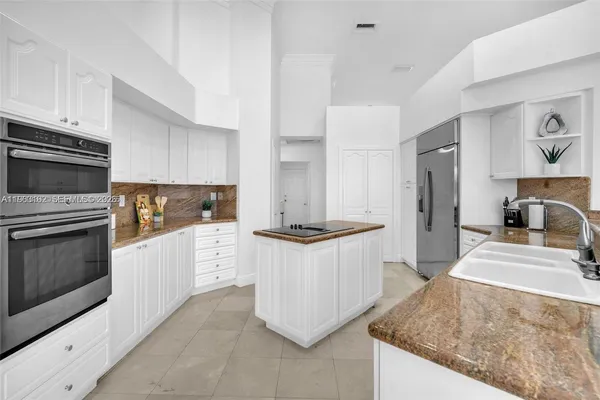 a kitchen with granite countertop a sink stove and refrigerator