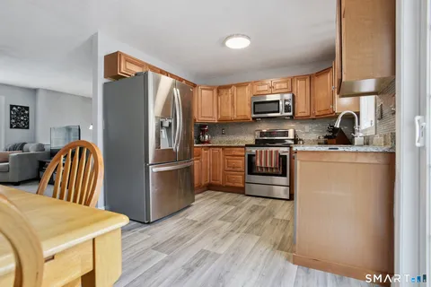 a kitchen with stainless steel appliances granite countertop a refrigerator a stove a sink dishwasher and a refrigerator with wooden floor