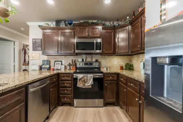 a kitchen with stainless steel appliances granite countertop a stove a sink and a microwave