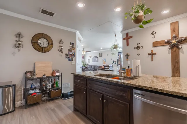 a kitchen with kitchen island granite countertop a sink a stove and wooden floor