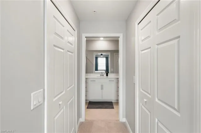 a view of a hallway with wooden floor and a bathroom