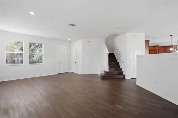 a view of empty room with wooden floor and stairs