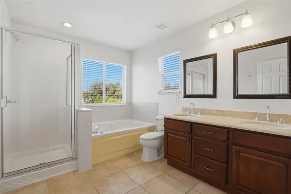 a bathroom with a double vanity sink a toilet a mirror and shower