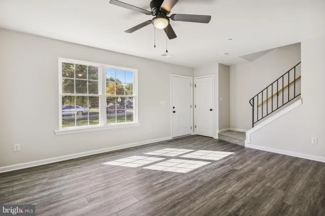 a view of an empty room with window and wooden floor